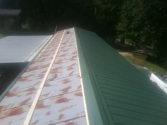 Old rusted panels beside newly installed green metal roofing — Wind Damage Roof Repair by Roofing Brothers in Mason